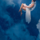 Femme en robe blanche flottant dans un ciel étoilé bleu profond, entourée de nuages, dans une ambiance onirique et spirituelle.